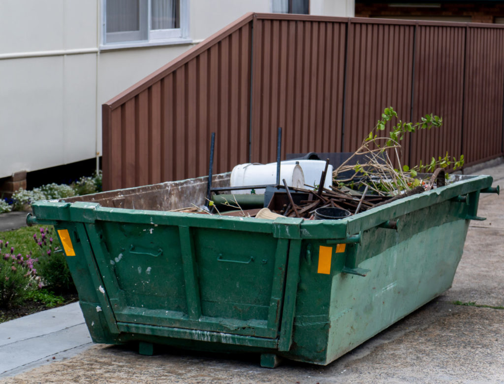 Skip bin with household waste rubbish on a front yard. House clean up concept.